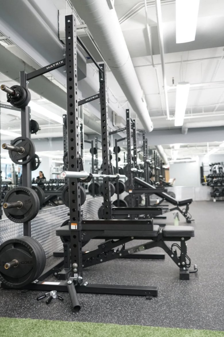 Matrix squat racks and benches along the University Row training floor