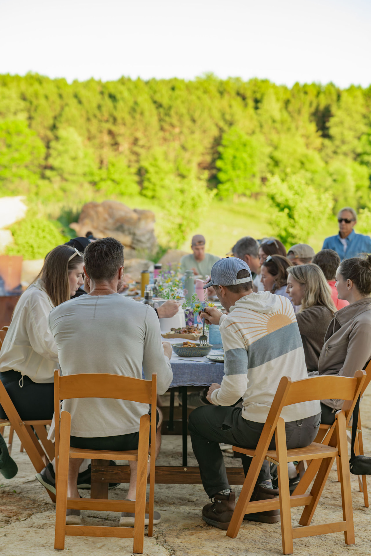 Retreat guests sharing an outdoor meal at a long communal table at Flynn Creek Farm