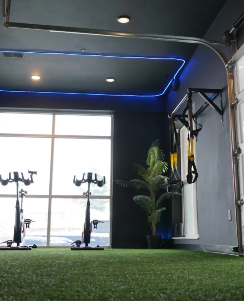 The indoor turf with spin bikes and TRX straps under blue accent lighting at PKFit Park Street