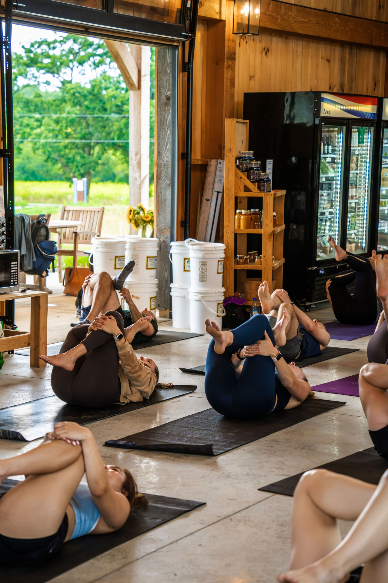 Retreat guests resting through a guided stretch inside an open barn at Flynn Creek Farm