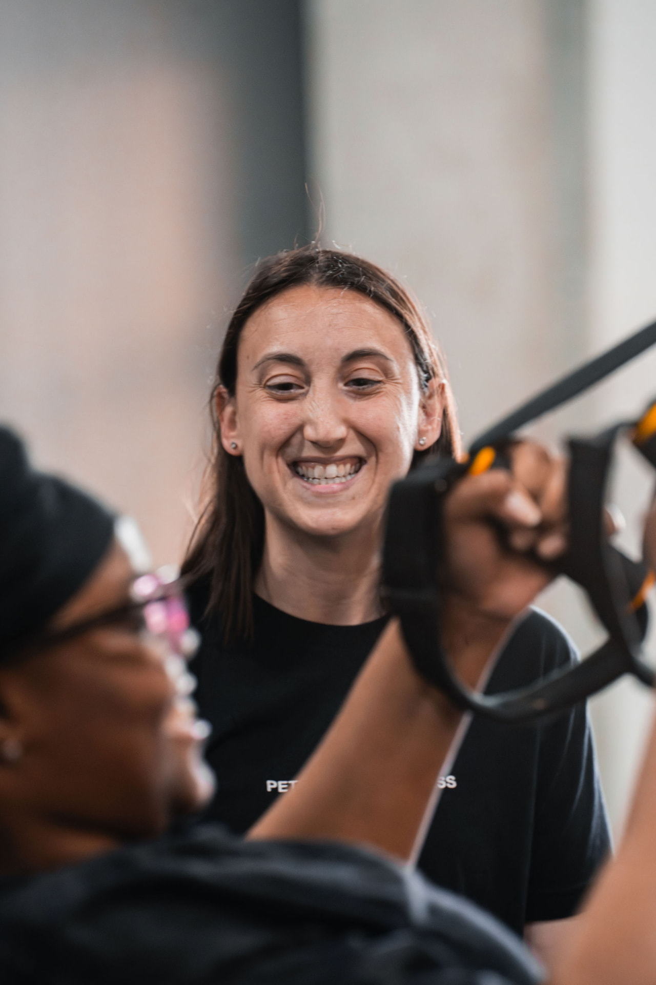 A smiling PKFit trainer guiding a member through suspension strap training