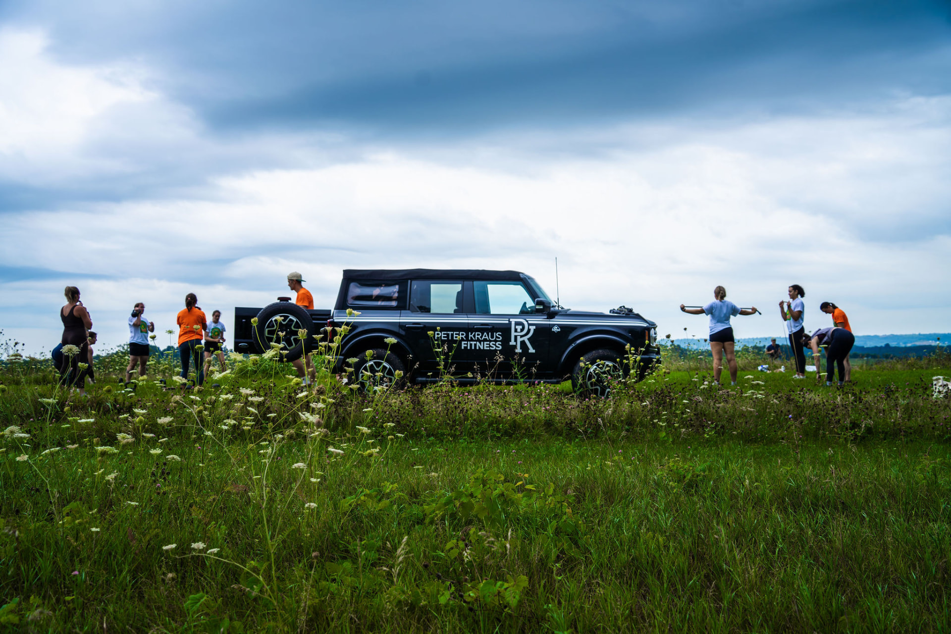 PKFit members training outdoors on a grassy hilltop around the PKFit vehicle