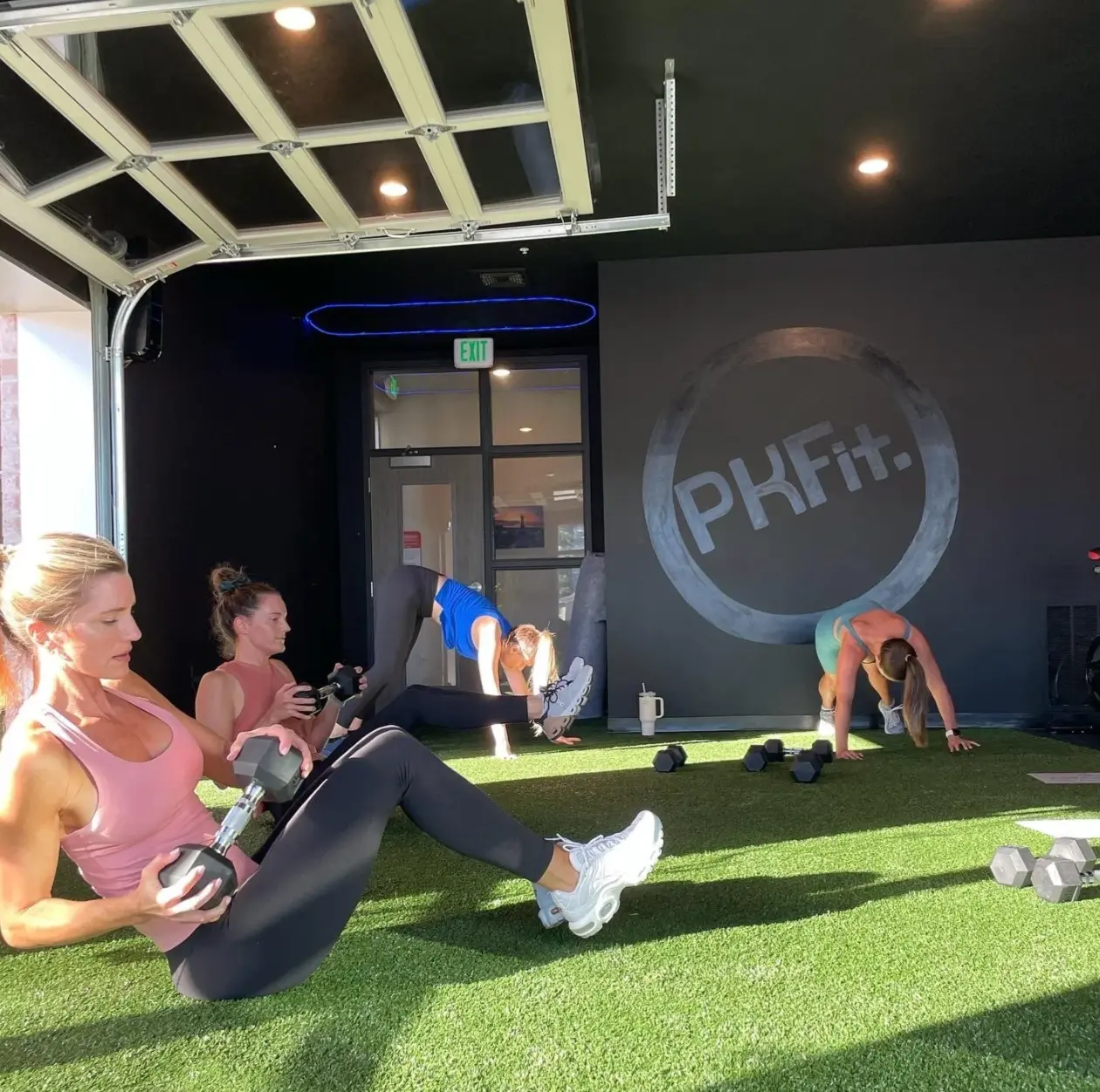 A group turf class with dumbbells under the open garage door at PKFit Park Street