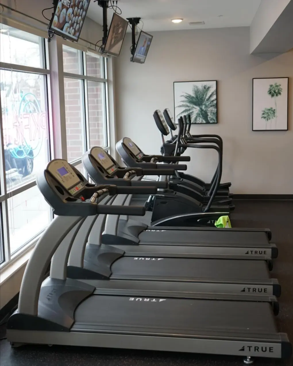 True treadmills and ellipticals along the front windows at PKFit Park Street