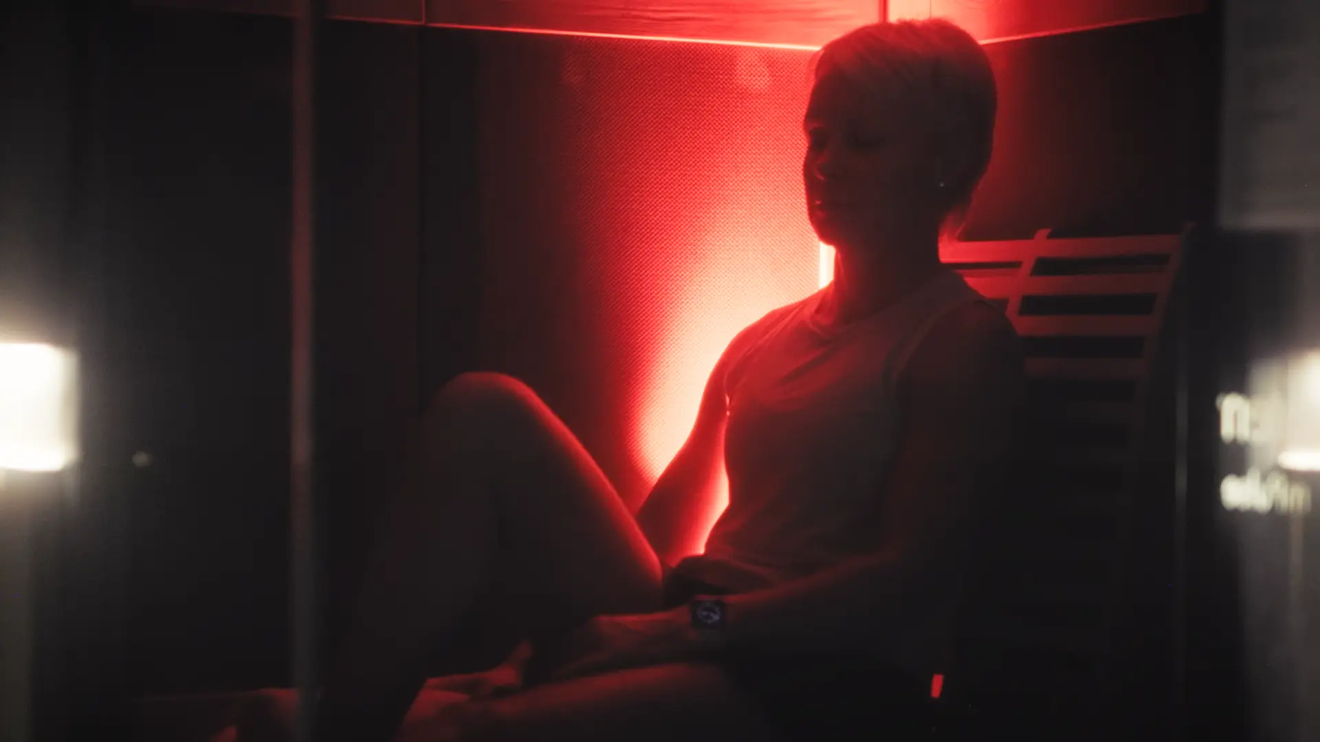 A PKFit member resting inside a red-lit infrared sauna