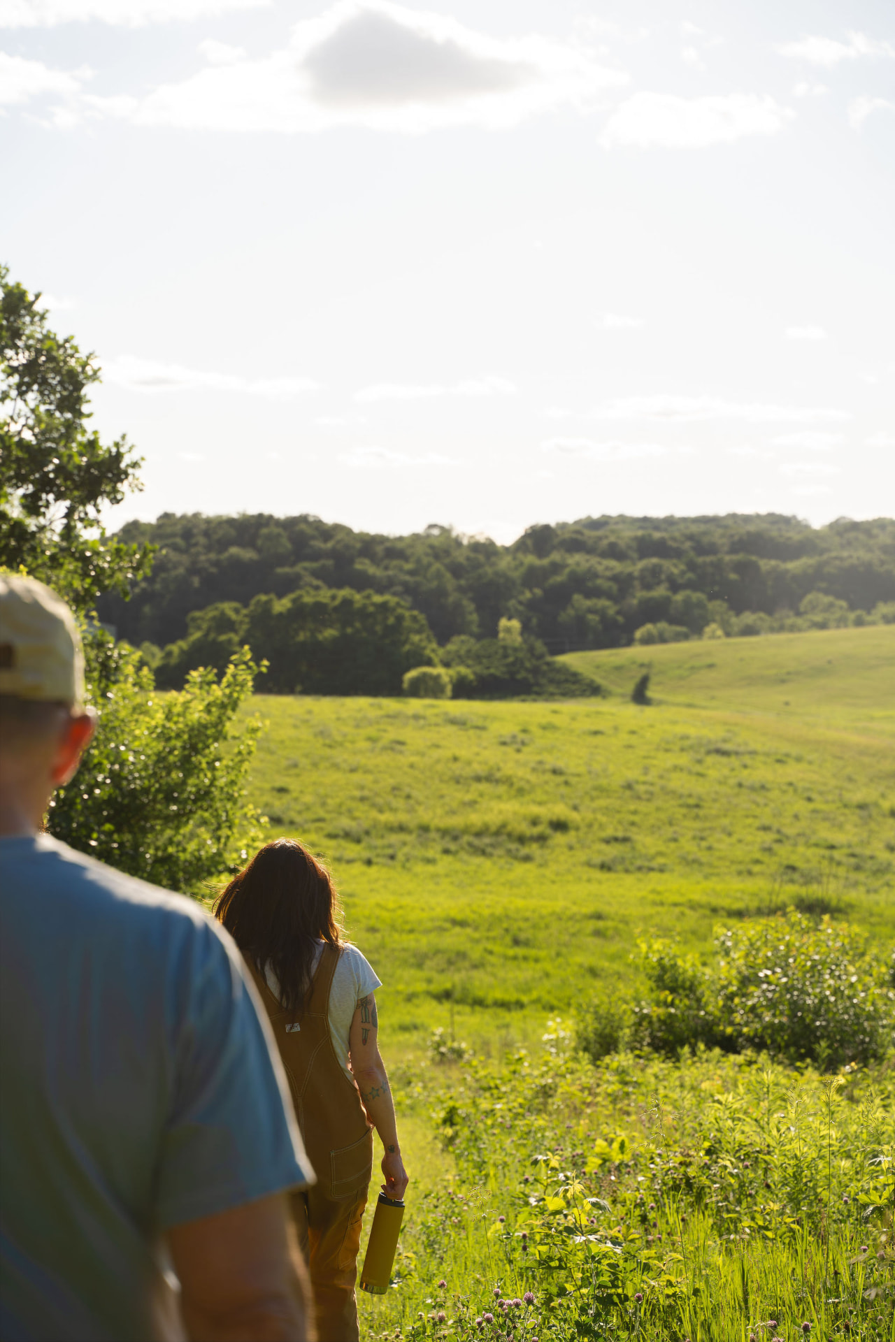 Two retreat guests walking down a grassy hillside toward open pastures at Flynn Creek Farm