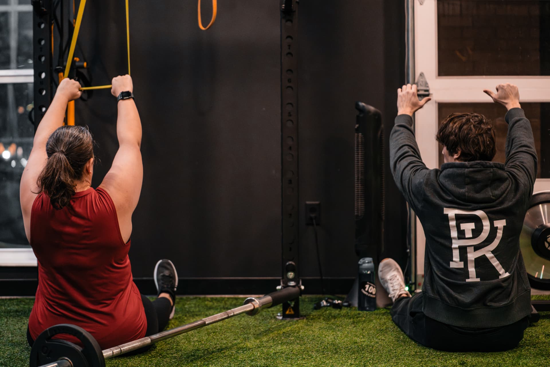 Two PKFit members training together on the gym turf