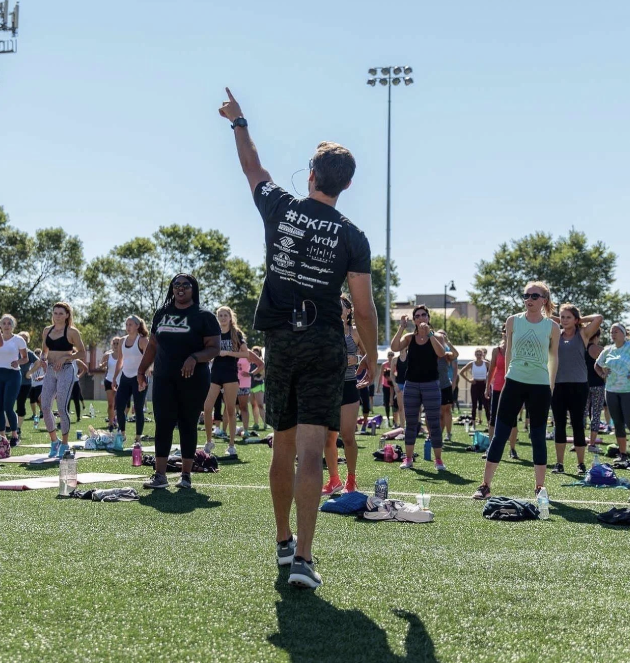 A PKFit coach leading an outdoor group class on the field
