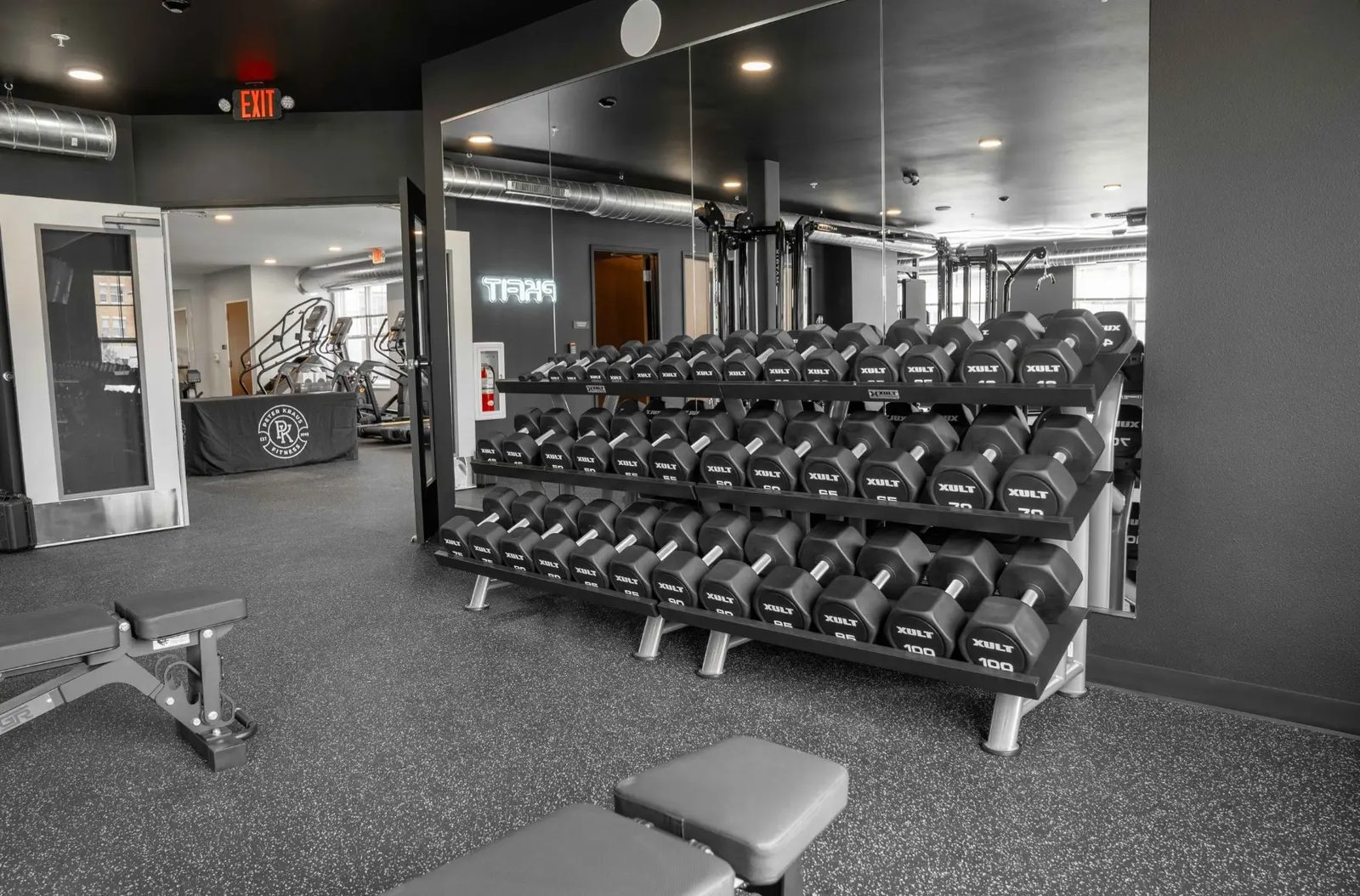 The dumbbell rack at PKFit Verona reflected in the mirrored wall