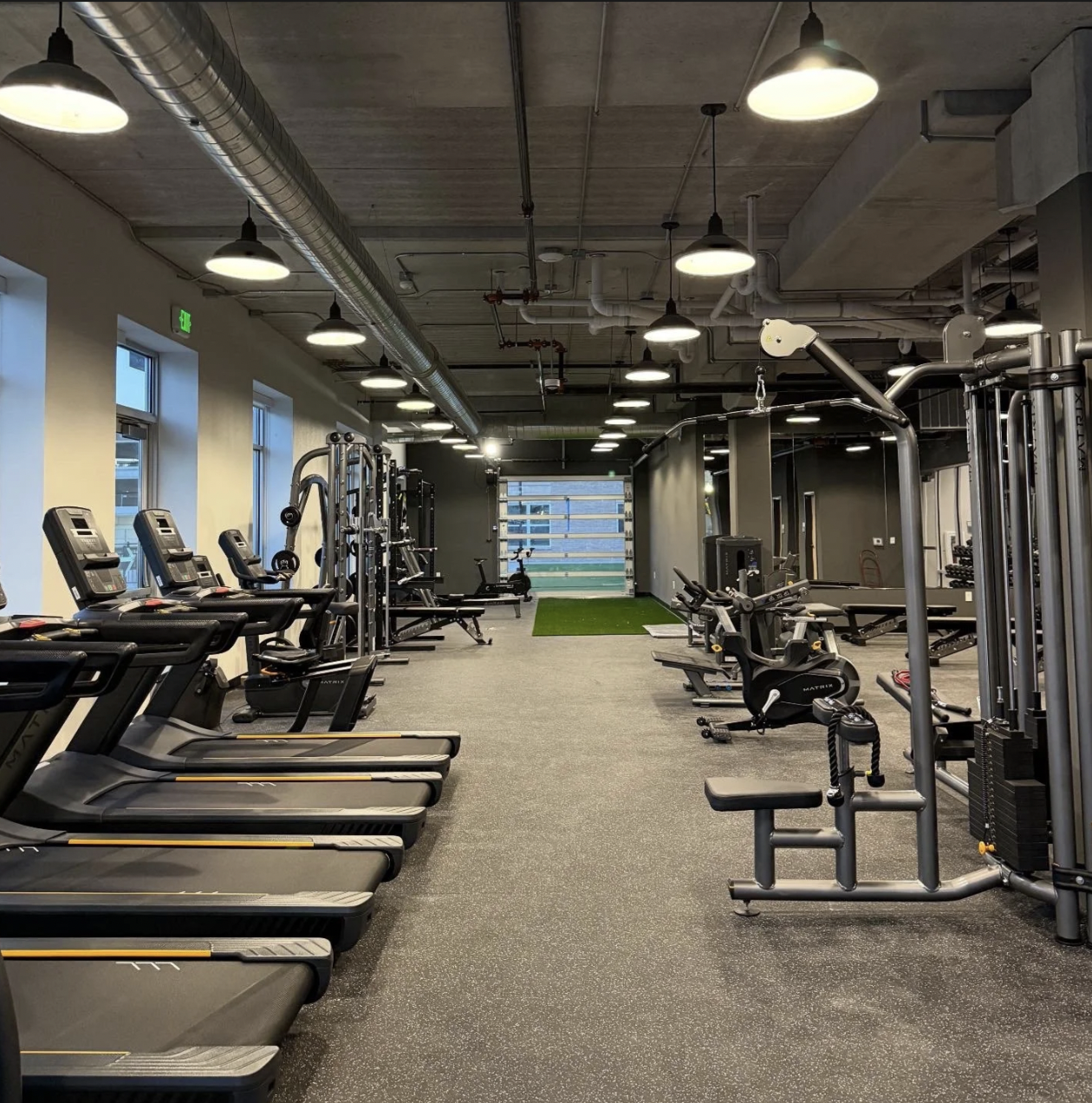 The PKFit Oshkosh gym floor with treadmills, cable machines, and an open garage door