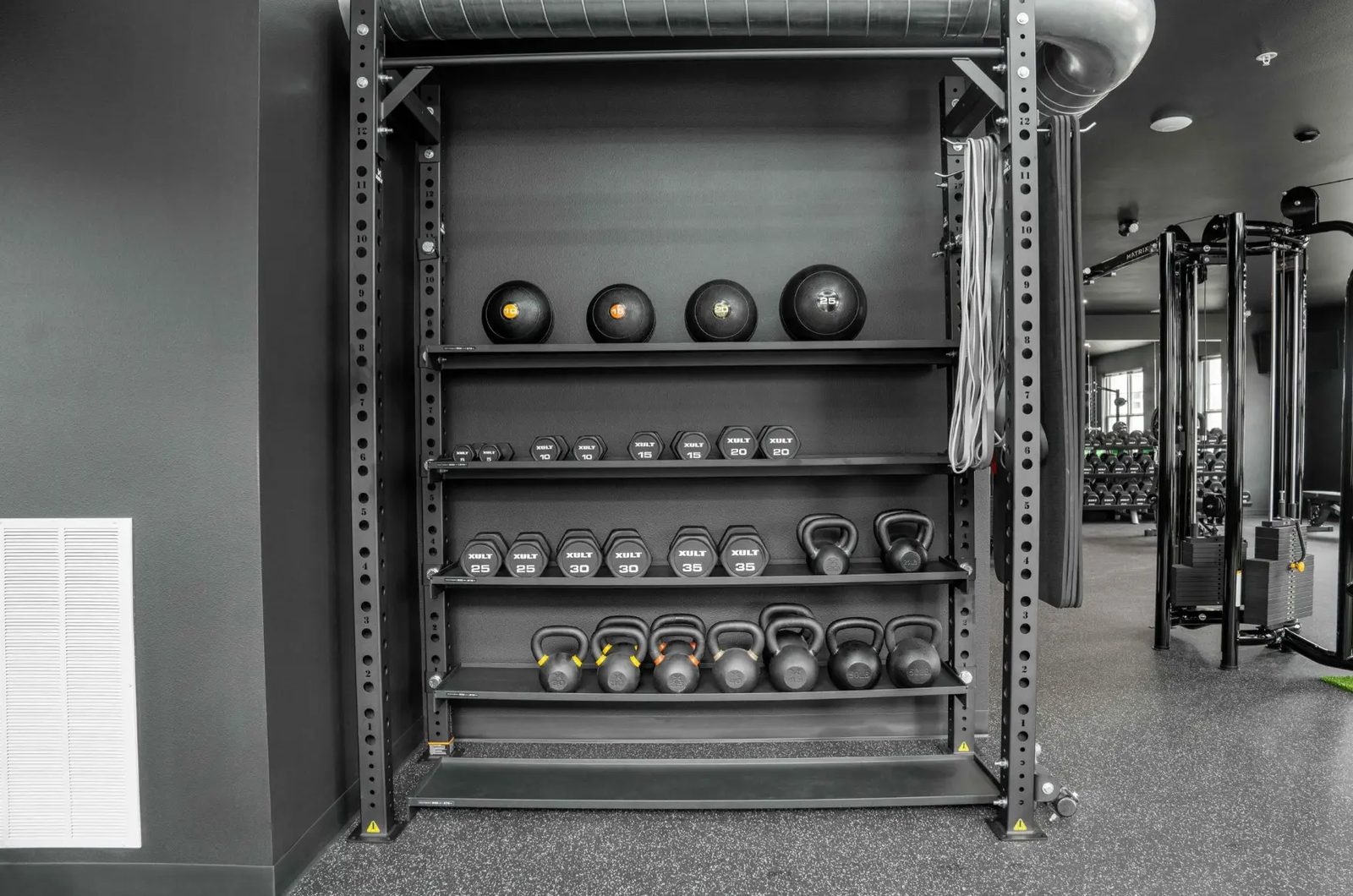 Medicine balls, dumbbells, and kettlebells on the storage rack at PKFit Verona