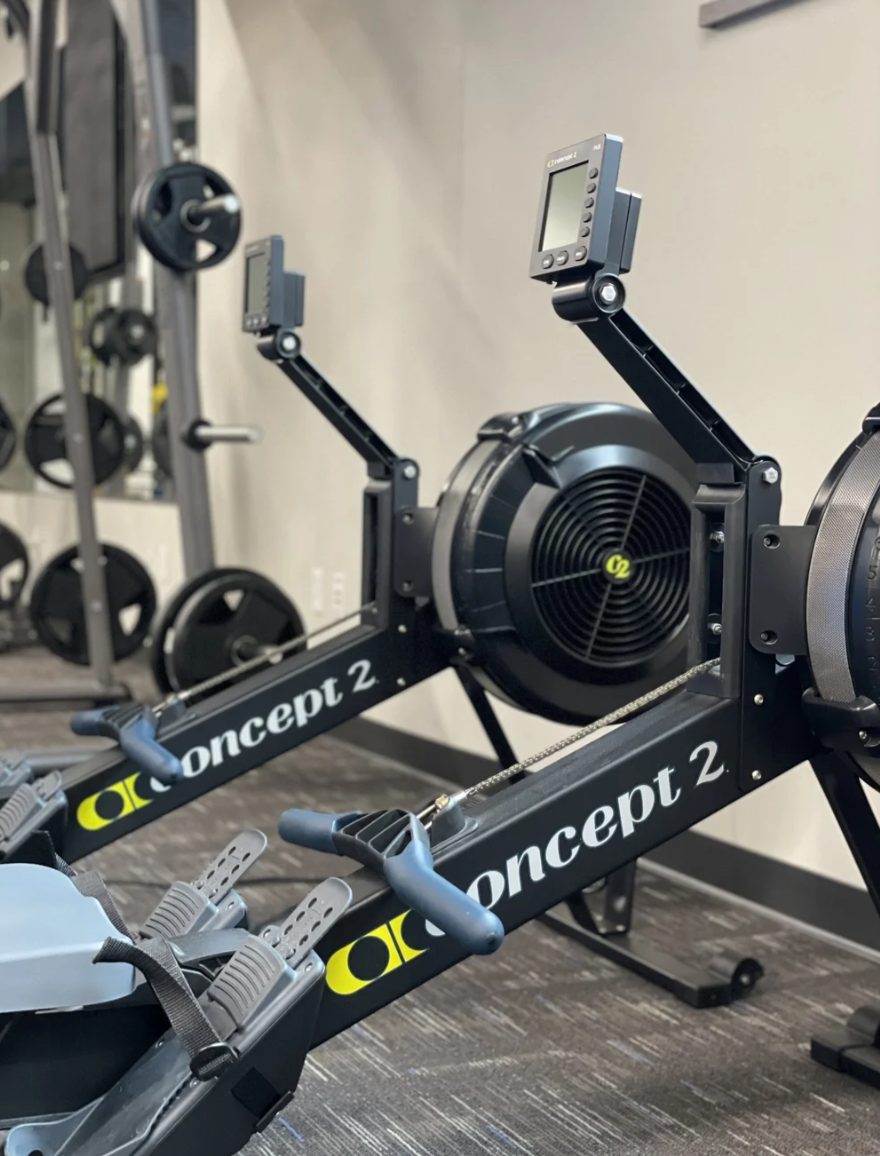 Two Concept2 rowing machines on the PKFit Madison East floor, reflected in the mirror