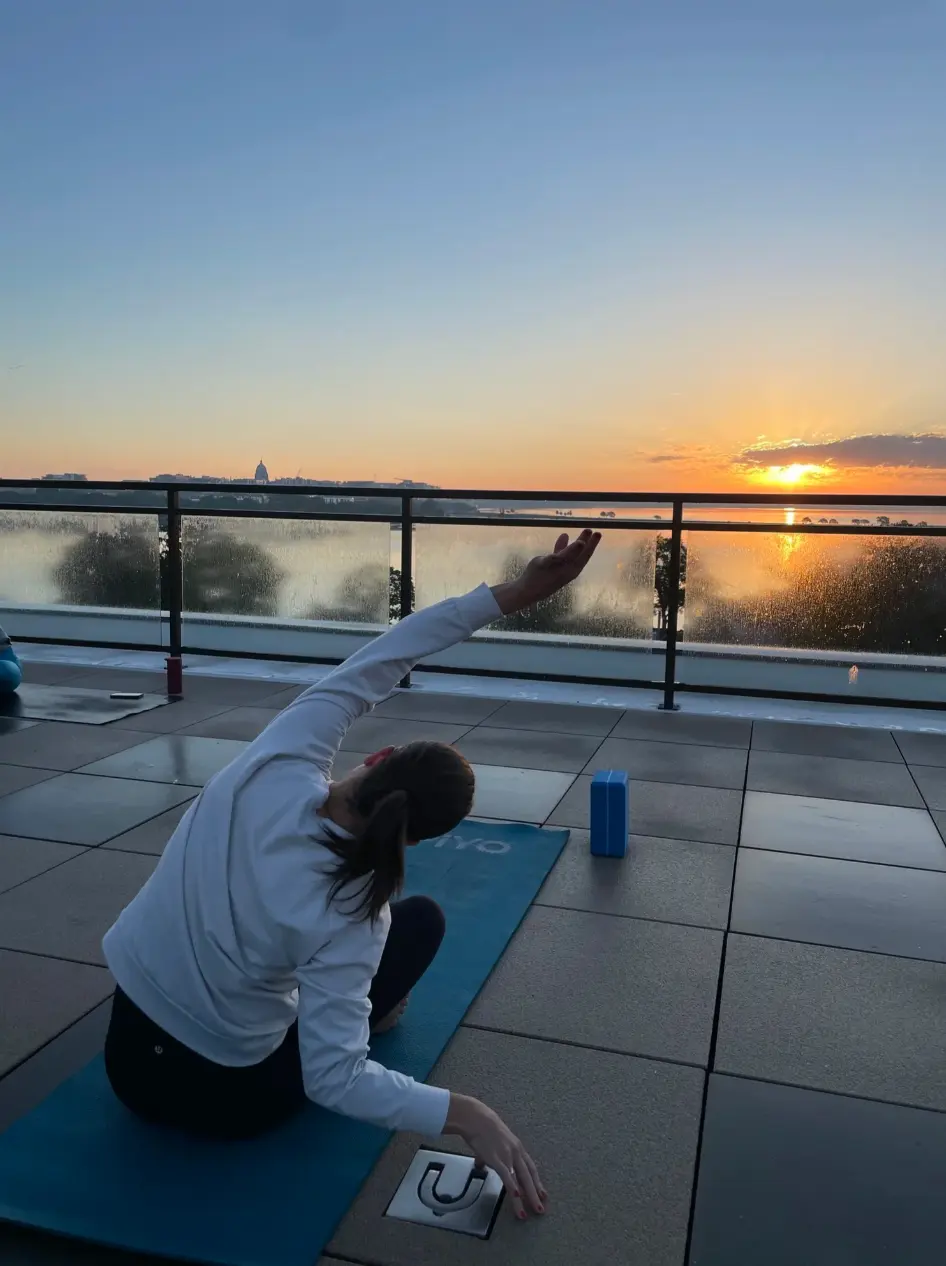 A member practicing rooftop yoga as the sun rises over Lake Monona